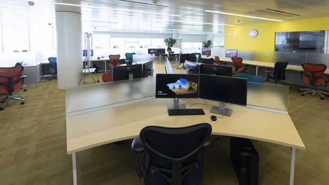 Double screen computer workstation with a large desk and office chair.