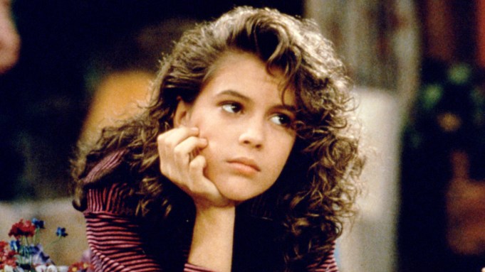 A young Alyssa Milano looks bored with her chin resting in her palm in a still from 'Who's the Boss?'