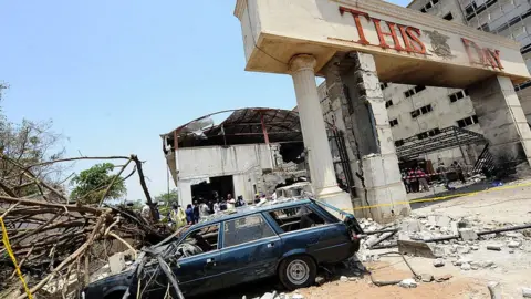 Getty Images A car destroyed by the bomb sits outside the premises of ThisDay