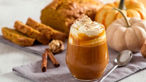 Ein Pumpkin Spice Latte neben Kürbissen und Kuchen