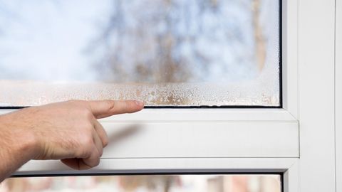 Person zeigt auf Fenster, das durch zu hohe Luftfeuchtigkeit beschlagen ist