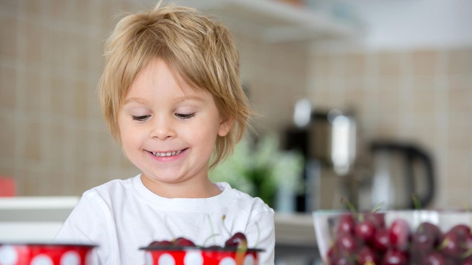 Ein kleiner Junge vor Schüsseln mit Obst und Gemüse