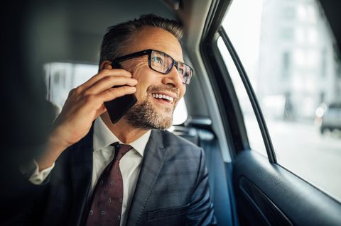 Mit dem Vodafone Business-Tarif von unterwegs arbeiten: Mann sitzt im Auto und telefoniert mit dem Handy.