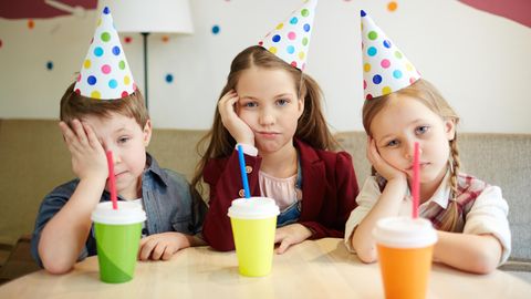 Drei Kinder mit Partyhütchen gucken genervt