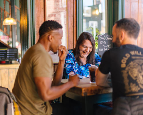 Two men and one woman smiling and laughing in a warm social setting