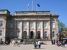 The front of a building built from grey stone with columns in front