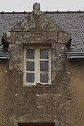 Photographie d'une lucarne au fronton triangulaire, sur fond de toit en ardoise.