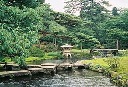 Een Japanse tuin met water, brug en lantaarn (yukimigata tōrō)