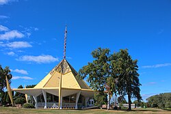 A round, bandstand-like structure with a pointed golden roof and a radio antenna that bears the word "WISCONSIN" in red letters placed along its length.