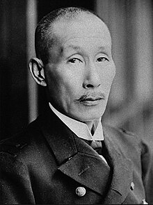 Photographie en noir et blanc de face d'un homme japonais regardant la caméra.