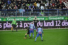 Joueur s'apprêtant à faire une remise en touche. Deux adversaires et un coéquipier sont visibles.