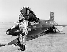 A black-and-white photo of Armstrong smiling outside of an X-15