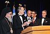 Carl Gershman gives an award to a young man, while three other men look on.