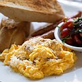 Scrambled eggs with grated cheese, tomato salad, and toasted baguette