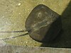 A brown, diamond-shaped ray with black spots and a whip-like tail, in shallow water next to a pier