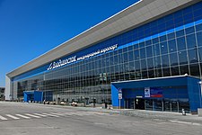 Photographie en contre-plongée d'un terminal d'aéroport bleu moderne, avec une grande baie vitrée en verre.