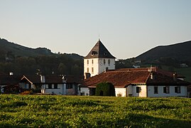 Photographie du clocher-tour d'une église au-dessus des maisons d'un village.