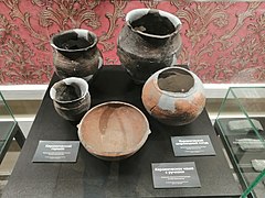 Des poteries noires et brunes ressemblant à des bols et vases, avec des indications en russe.