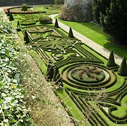 Photographie de jardins à la française, vue en plongée ; des buissons au premier plan.