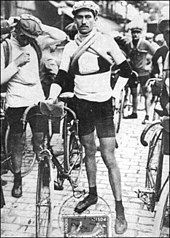 Photographie en noir et blanc d'un cycliste se tenant debout à côté de son vélo.