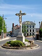 La croix Boissiée à l'est de la Grande-Rue, au milieu d'un carrefour, et l'ancien bâtiment administratif de l'usine Derolland-Delacoste.