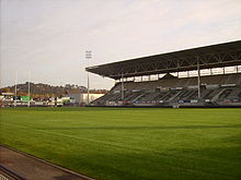 Un stade avec une tribune et le terrain est pris en photo depuis un côté.