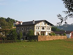 vue de trois quarts d'une maison à deux étages aux pans de bois vert.