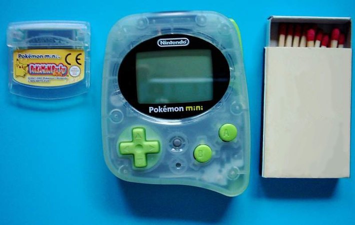 A Pokemon Mini with "Chikorita Green" trim and game cartridge. A matchbox is shown for scale.