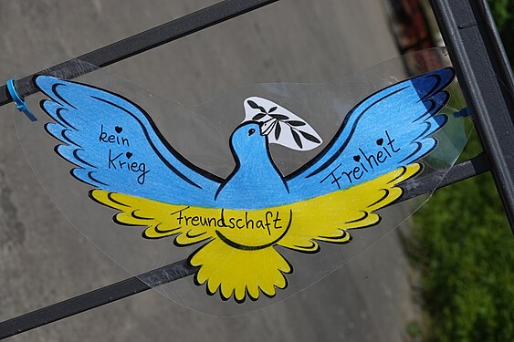 Dove of peace in the blue and yellow of the Ukrainian flag with the inscription “no war”, “love”, “friendship”, painted on a school gate in Jüterborg, Germany