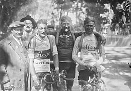 Trois cyclistes posant à l'arrivée, se tenant par l'épaule, à côté d'hommes en costume.