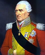 White haired man with red military jacket, decorated in yellow, with fancy epaulets on his shoulders, a ribbon sash, and military decorations.