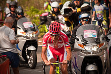 A man wearing an almost all red uniform while riding a bike.