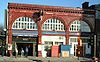 A red-bricked building with a dark blue, rectangular sign reading "LAMBETH NORTH STATION" in white letters all under a light blue sky