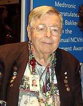 waist high portrait wearing a suit coat and Hawaiian shirt and lots of Mardi Gras-like necklaces and his Medtronic namebadge