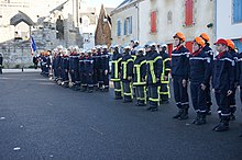 Photographie d'un peloton de pompiers lors d'une cérémonie.