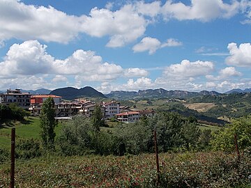 a view to a forested hill and to Monte San Severino (San Leo mountain chain)