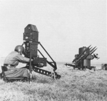 A two-wheeled trailer with four missiles on it. It has a radar dome, and a jerry can is attached to the trailer.