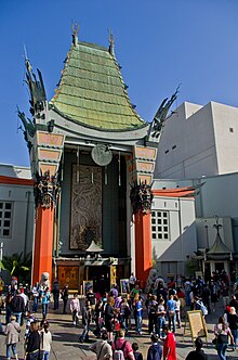 Photo d'un bâtiment dont la forme de l'entrée prend une architecture chinoise. Beaucoup de personnes pénètrent dans ce lieu.