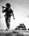 A French Foreign Legionnaire goes to war along the dry rib of a rice paddy, during a recent sweep through communist-held areas in the Red River Delta, between Haiphong and Hanoi. Behind the Legionnaire is a U.S. gifted tank. Pix., ca. 1954