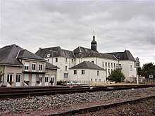 Photographie en couleurs d'un ensemble de bâtiments dont les toits en ardoise sont surmontés d'un clocheton.