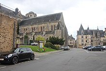 Vue d'une place avec édifices anciens et une cathédrale à l'arrière-plan à gauche.