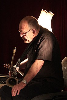 Seated man holding a saxophone