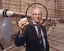 Picture of Paul MacCready holding a ring shaped object to the camera