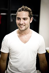 A picture of a man with his hair tied back and wearing a white T-shirt