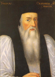 Portrait of Archbishop Cranmer as an elderly man. He has a long face with a flowing white beard, large nose, dark eyes and and rosy cheeks. He wears clerical robes with a black mantle over full white sleeves and has a doctoral cap on his head