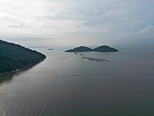 A patch of land being reclaimed from the sea, with an island visible in the background.