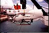 A white submarine is attached to a pole and ready to be dropped into the ocean.