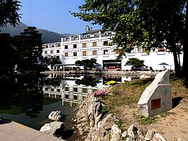 Un bâtiment blanc se reflète dans l'eau d'un lac, dans un cadre champêtre.