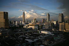 Many low-rise buildings in the foreground, with an elevated rail line and several medium box-saped buildings beyond; many tall buildings in the background