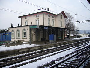 Two-story building with gabled roof next on side platform